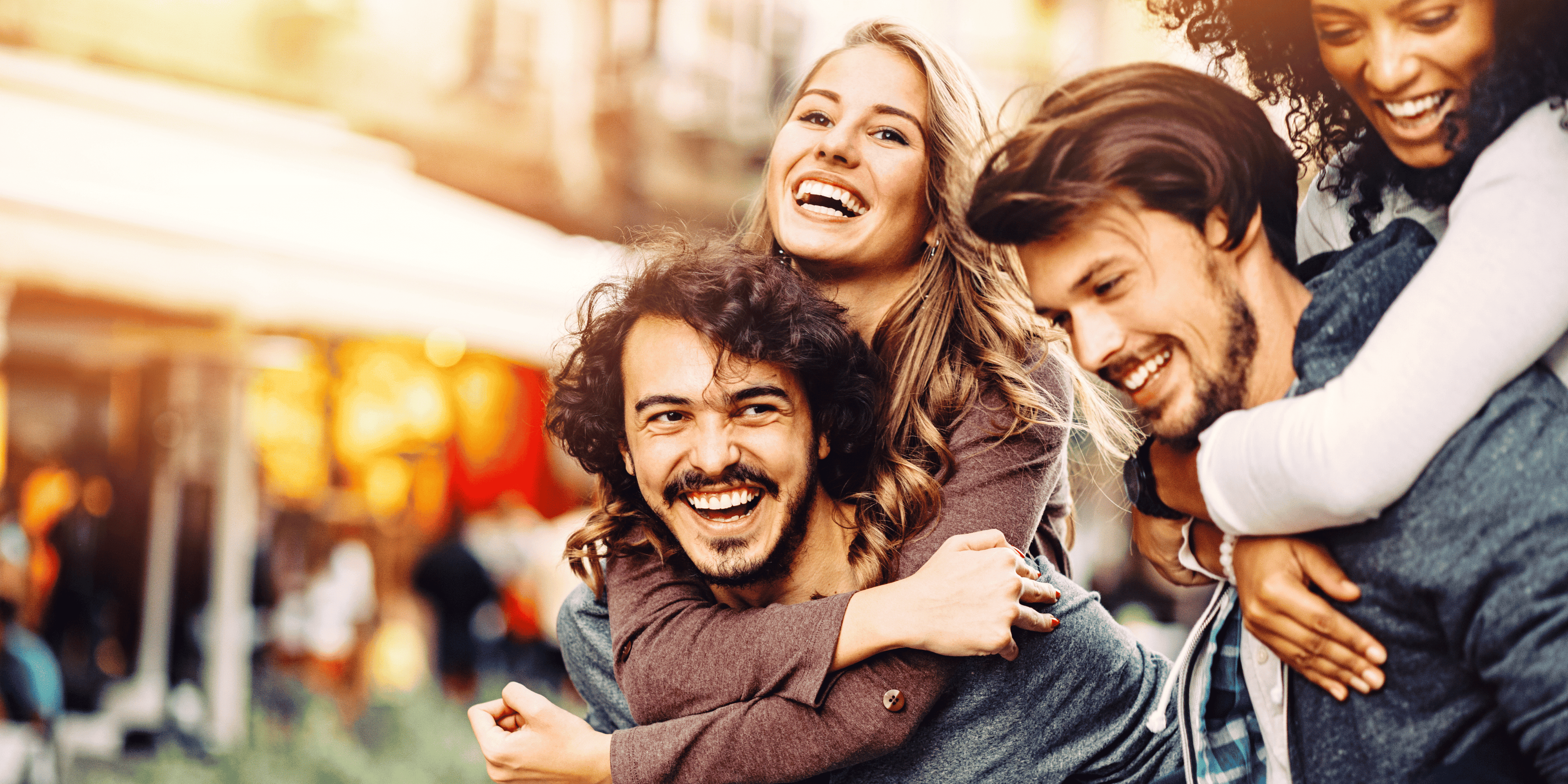 Group of four friends posing together with a blurred city street background