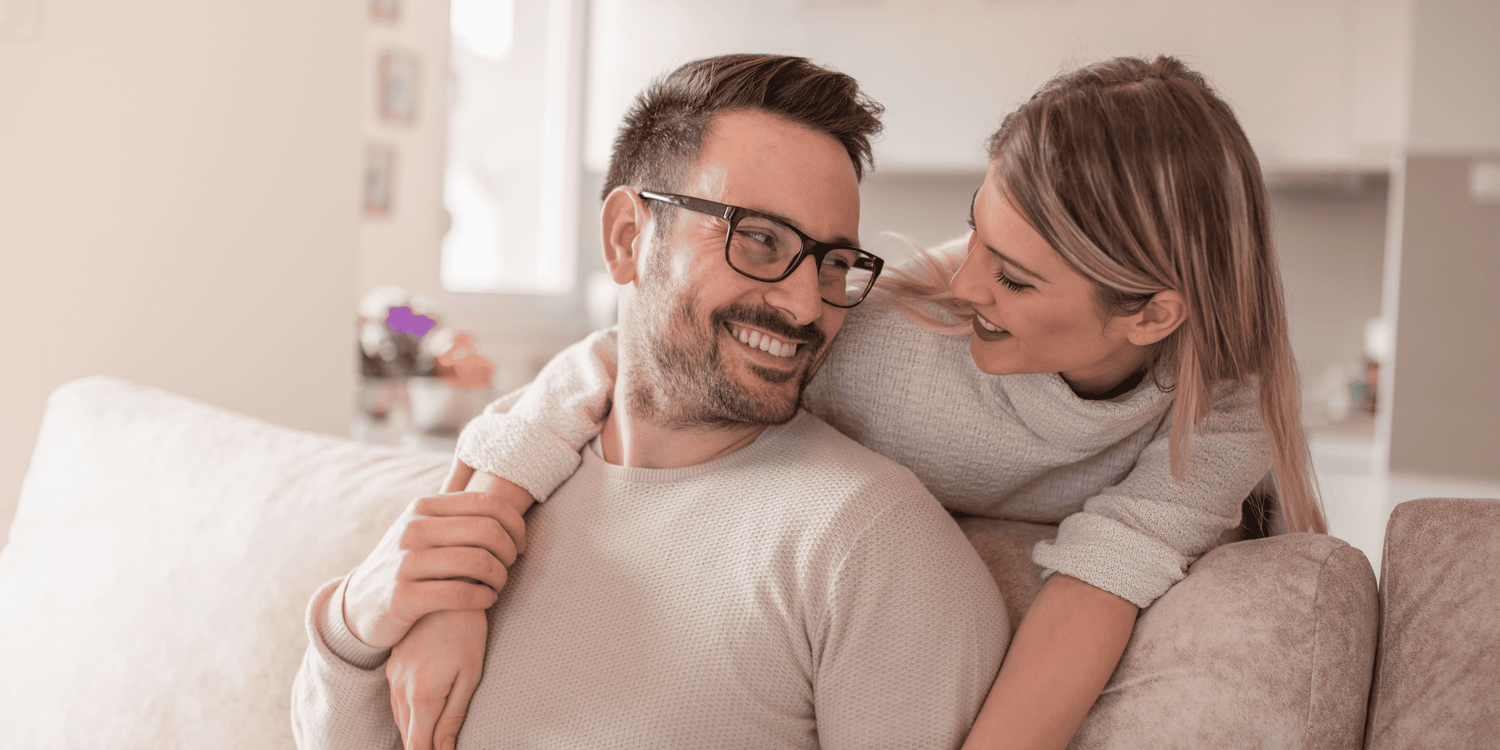 Man and woman sitting close together on a couch in a cozy living room.