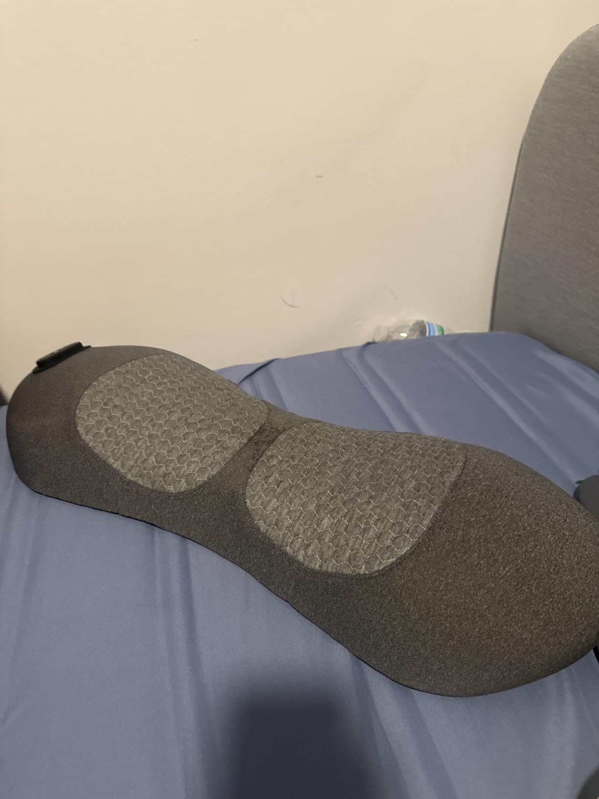 Gray massage pillow on a blue surface with a neutral background