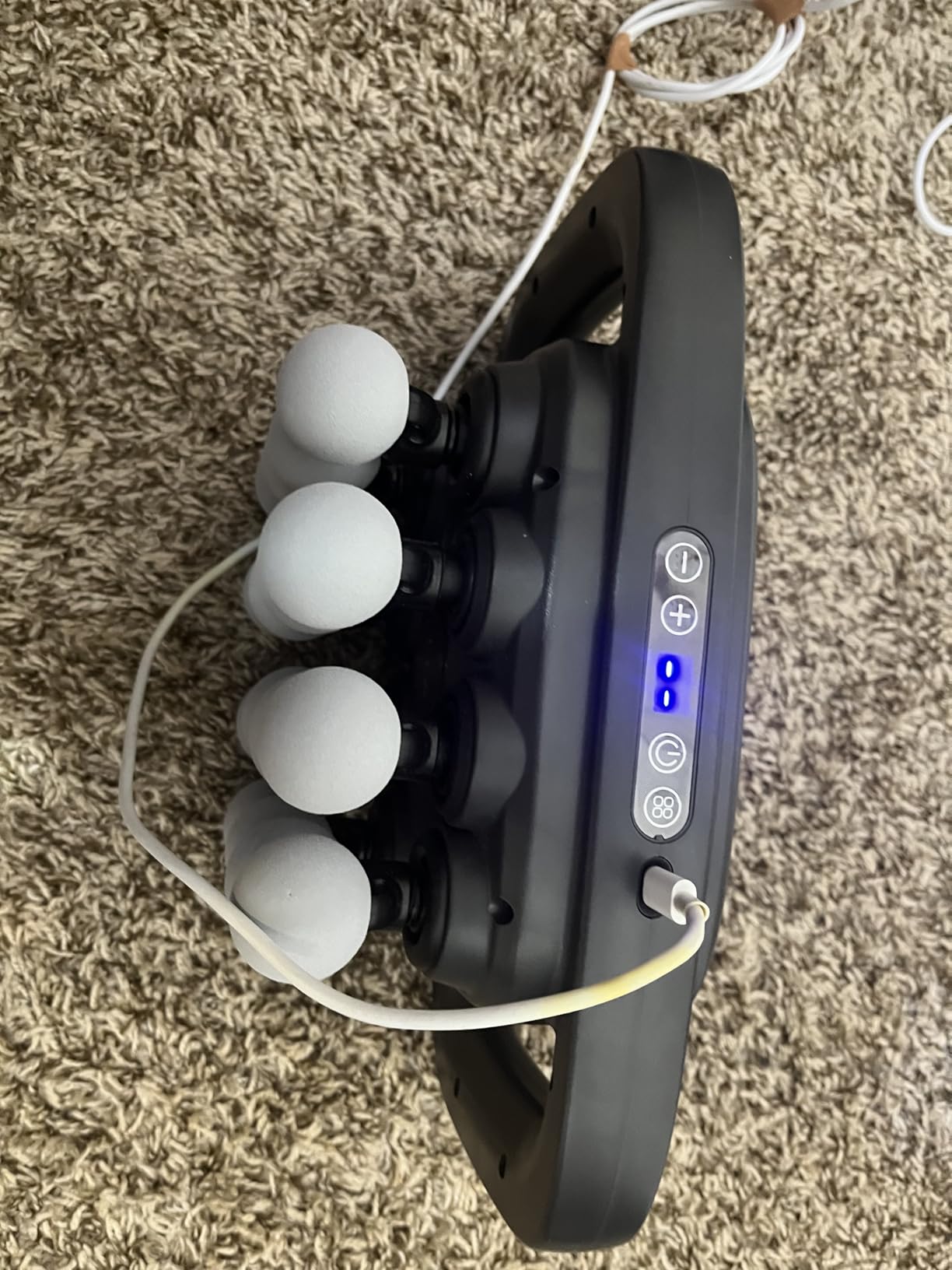 Wave massage gun with white balls on a carpet