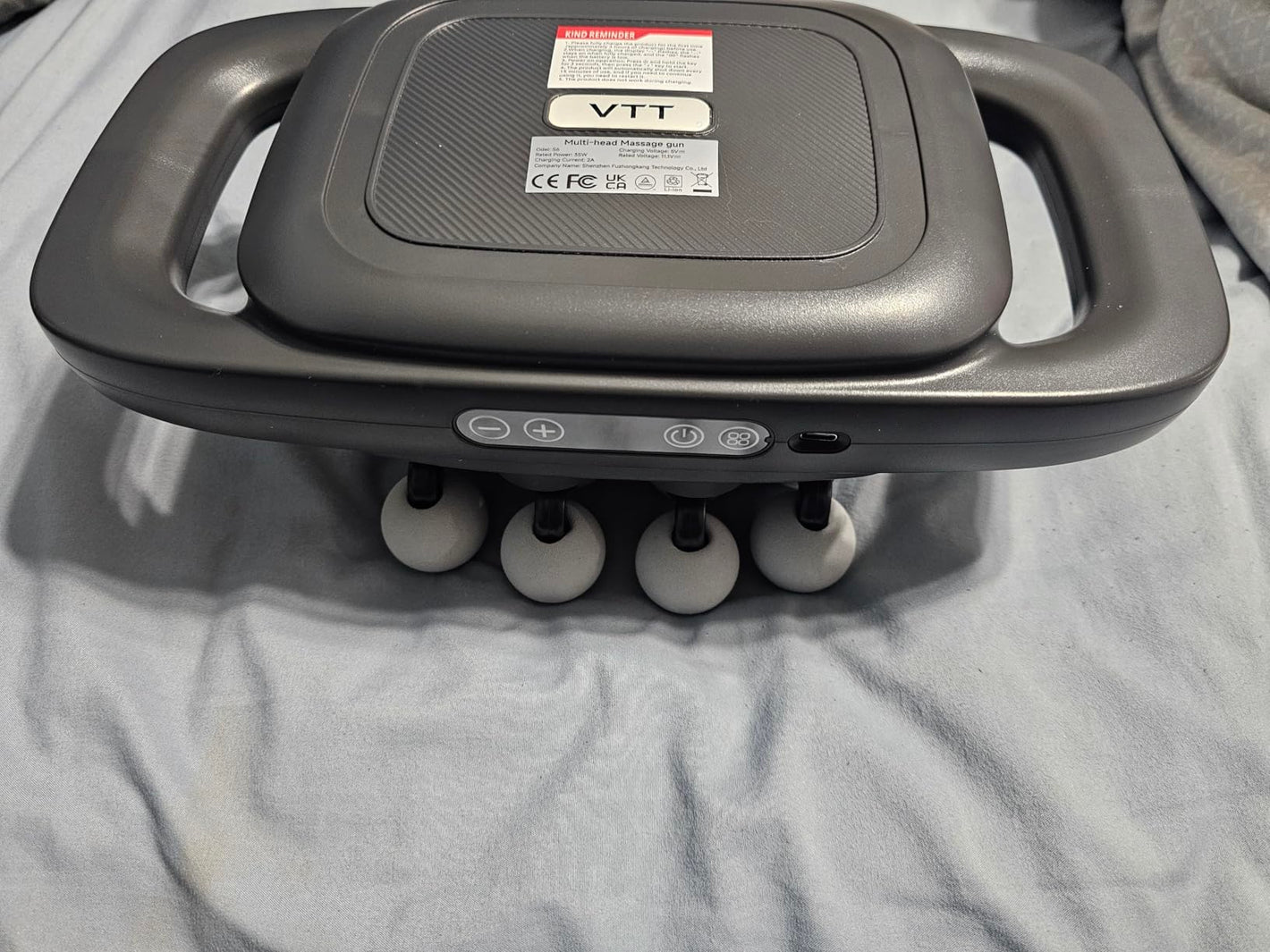 Gray massage device with handles on a gray surface
