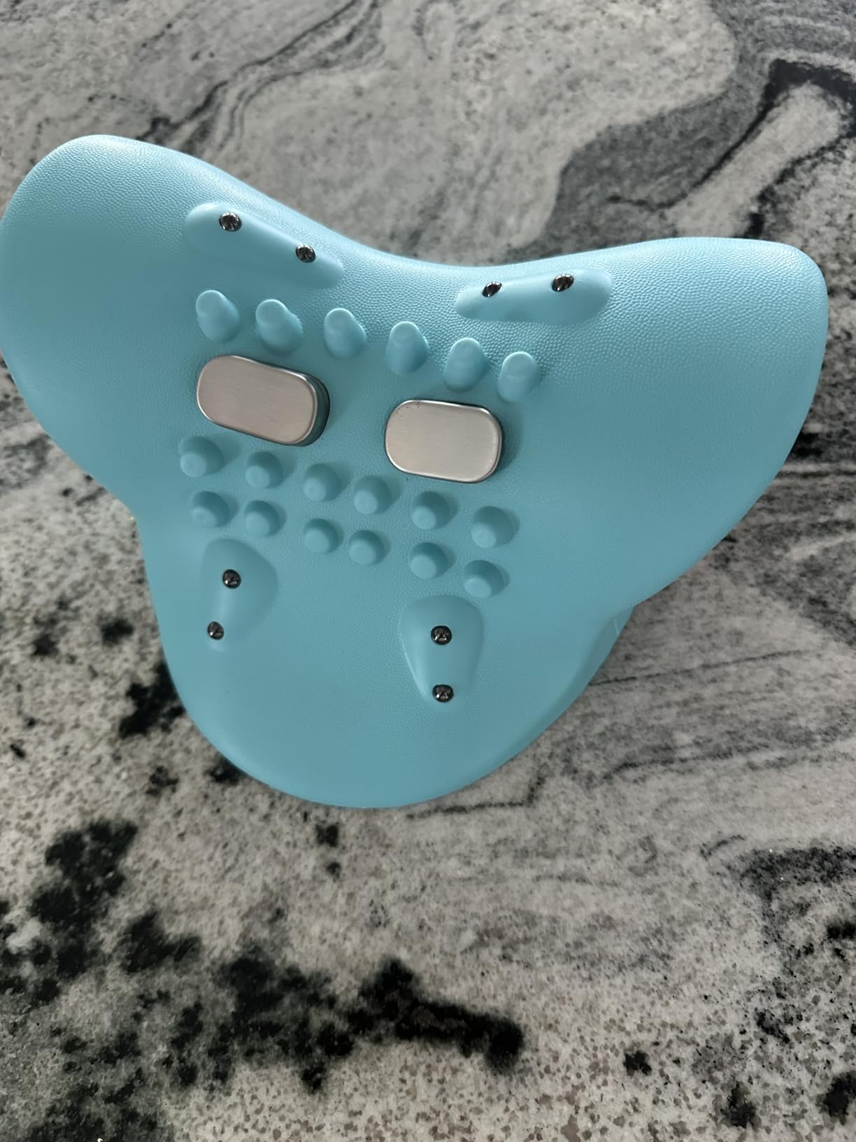 Light blue device with textured surface and metallic buttons on a gray marble background