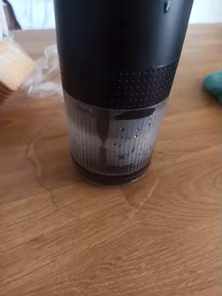 Black and clear cylindrical container on a wooden surface